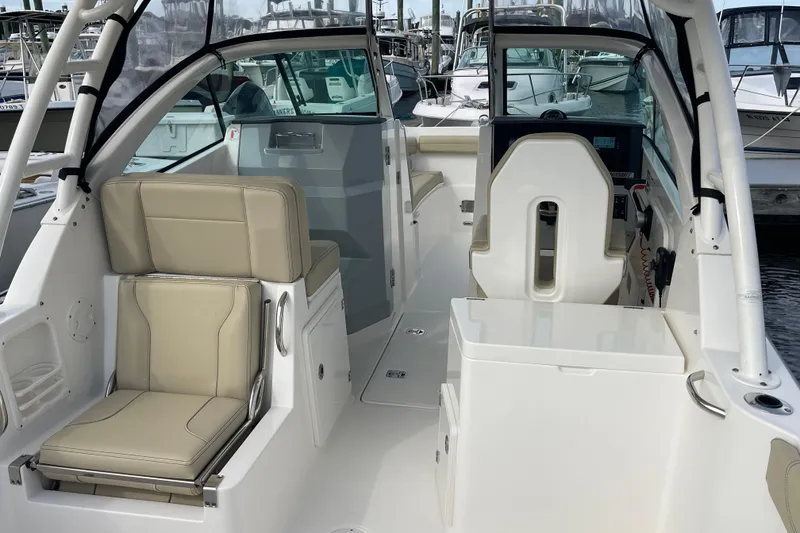 Slide: The Image of 2020 Pursuit DC 235 Dual Console boat interior with beige seating and helm station. - 1