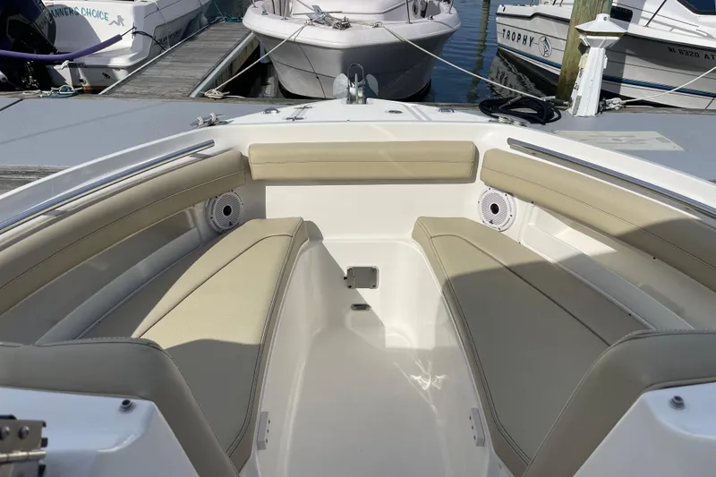 Slide: The Image of 2020 Pursuit DC 235 Dual Console boat interior with beige seating at dock. - 10