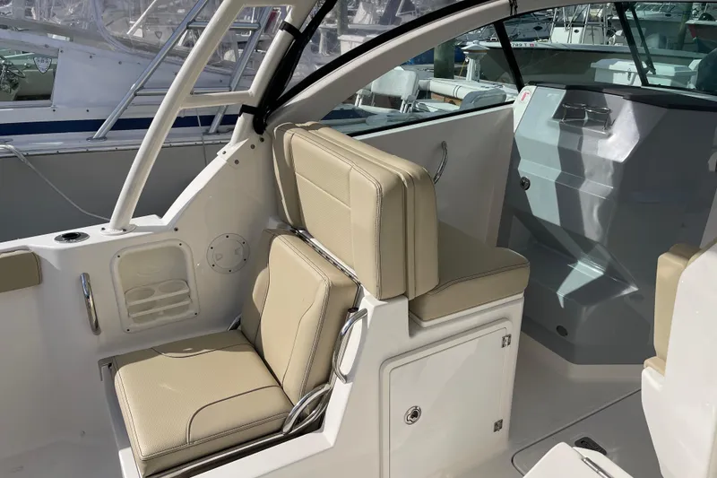 Slide: The Image of 2020 Pursuit DC 235 Dual Console boat interior with beige seating and storage compartments. - 14