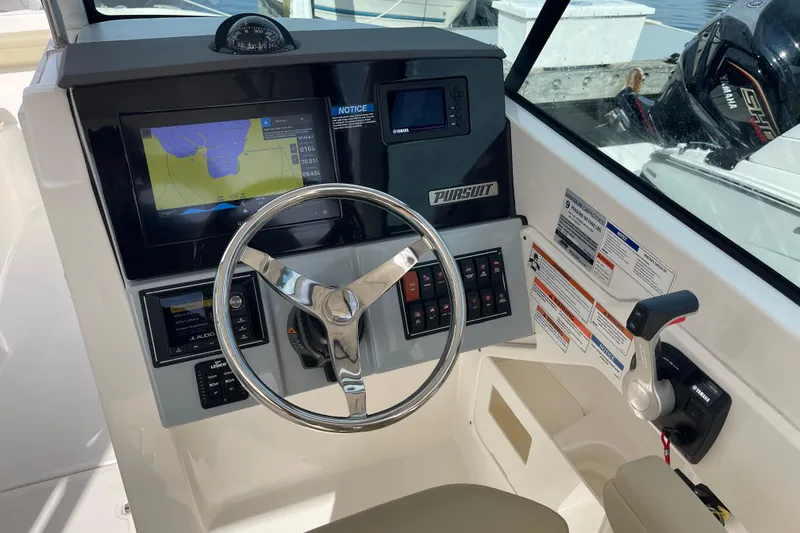 Slide: The Image of 2020 Pursuit DC 235 Dual Console boat dashboard with steering wheel and navigation display. - 16