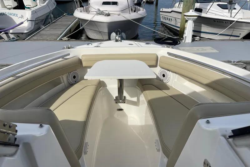 Slide: The Image of 2020 Pursuit DC 235 Dual Console boat interior with seating and table at dock. - 23