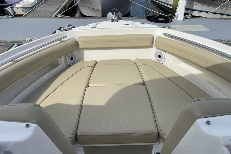 Slide: The Image of 2020 Pursuit DC 235 Dual Console boat interior with beige cushioned seating at dock. - 25