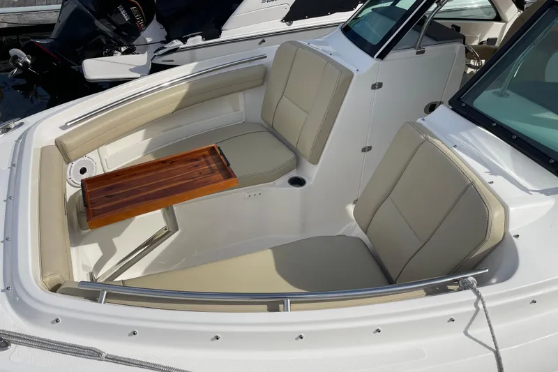 Slide: The Image of 2020 Pursuit DC 235 Dual Console boat interior with beige seating and wooden table. - 4