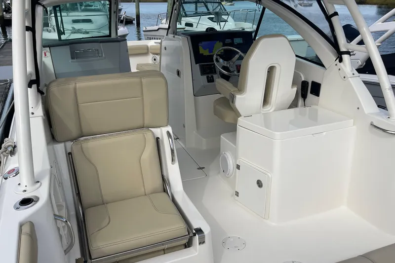 Slide: The Image of 2020 Pursuit DC 235 Dual Console boat interior with beige seating and modern dashboard. - 45
