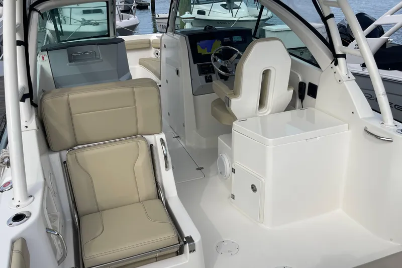 Slide: The Image of 2020 Pursuit DC 235 Dual Console boat interior with beige seating and modern dashboard. - 46