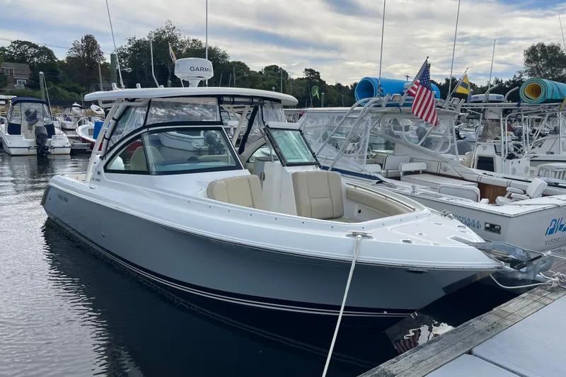 Slide: The Image of 2020 Pursuit DC 235 Dual Console boat docked at marina, featuring sleek design and American flag. - 48