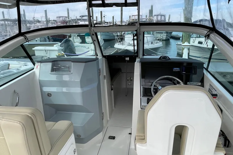 Slide: The Image of 2020 Pursuit DC 235 Dual Console boat interior with helm and seating at marina. - 53