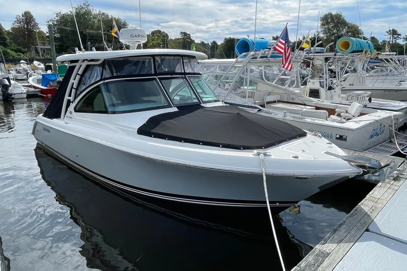Slide: The Image of 2020 Pursuit DC 235 Dual Console boat docked in a marina, featuring sleek design. - 61