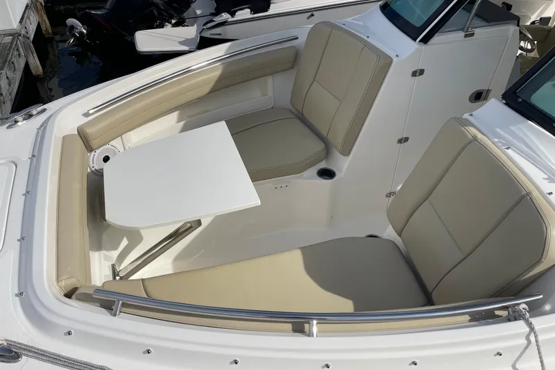 Slide: The Image of 2020 Pursuit DC 235 Dual Console boat interior with beige seating and a white table. - 8