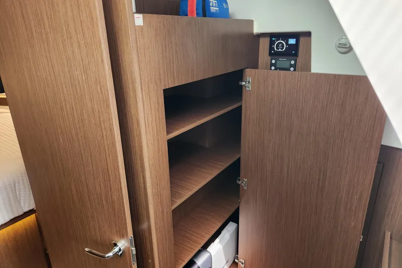 Slide: The Image of 2022 Beneteau Antares 11 interior with open wooden cabinet and control panel. - 15