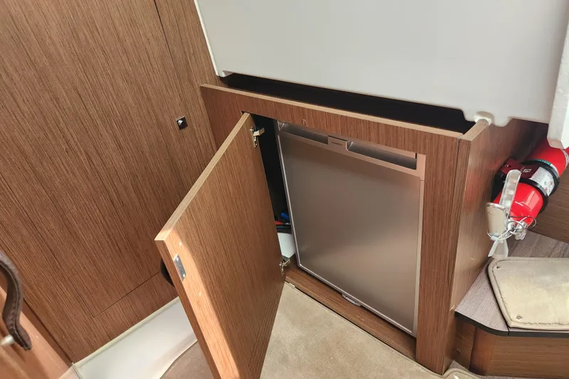 Slide: The Image of 2022 Beneteau Antares 11 interior with open cabinet and fire extinguisher. - 16