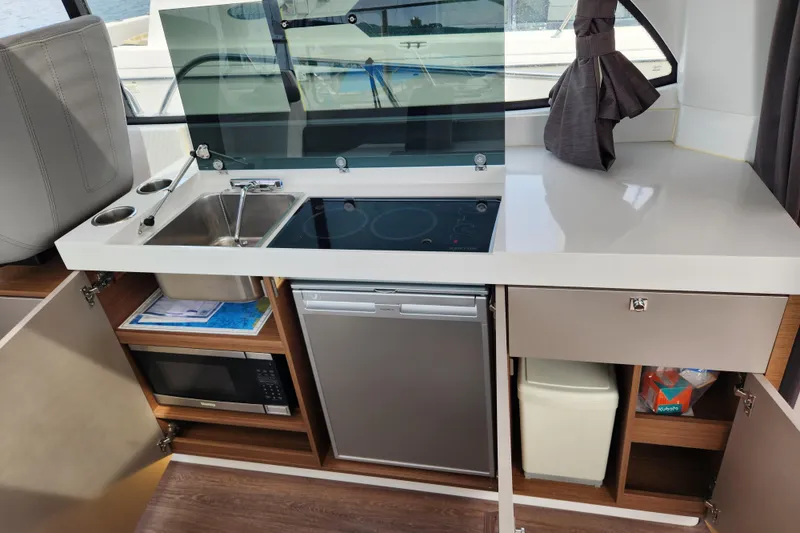 Slide: The Image of Compact kitchen in 2022 Beneteau Antares 11 with sink, stove, fridge, and microwave. - 24