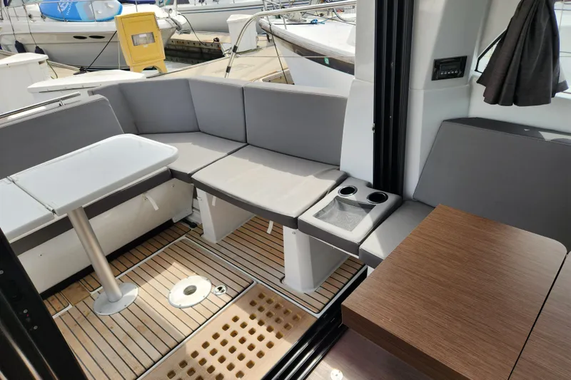 Slide: The Image of 2022 Beneteau Antares 11 interior with gray seating, wooden flooring, and a compact table. - 27