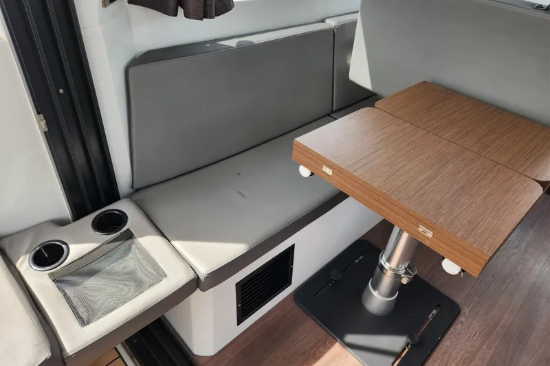 Slide: The Image of Interior of 2022 Beneteau Antares 11 with wooden table and gray seating. - 39