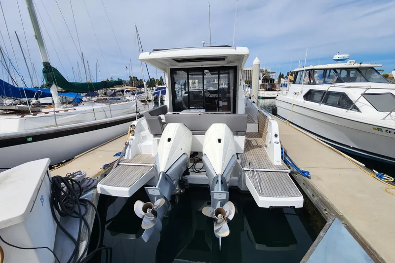 Slide: The Image of 2022 Beneteau Antares 11 docked at marina, rear view with dual outboard engines. - 8