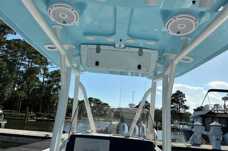 Slide: The Image of 2019 Sea Hunt Ultra 225 boat interior with speakers and storage, docked at marina. - 17