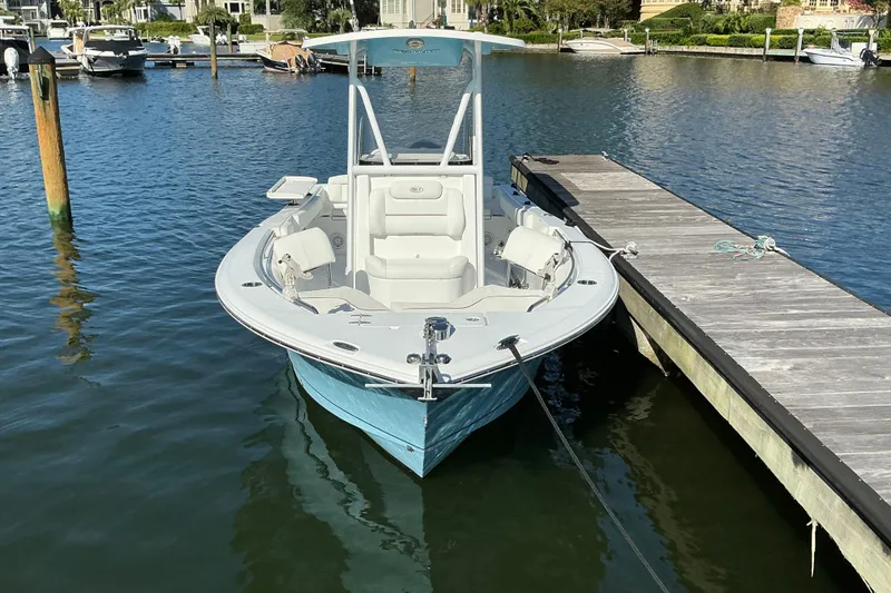 Slide: The Image of 2019 Sea Hunt Ultra 225 boat docked in a marina, calm water, sunny day. - 8