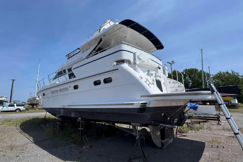 Slide: The Image of 2000 Horizon E56 yacht on dry dock, alongside smaller sailboat, under clear blue sky. - 4