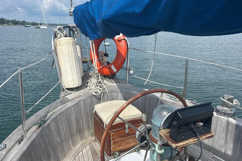 Slide: The Image of 1980 Hans Christian 43 sailboat cockpit with wooden wheel, life preserver, and blue canopy. - 26