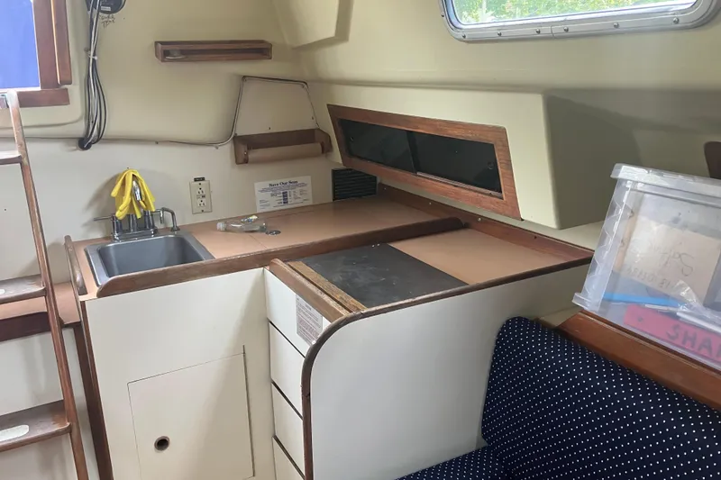 Slide: The Image of Interior of 1983 Pearson 303 Sloop, featuring compact kitchen and seating area. - 6