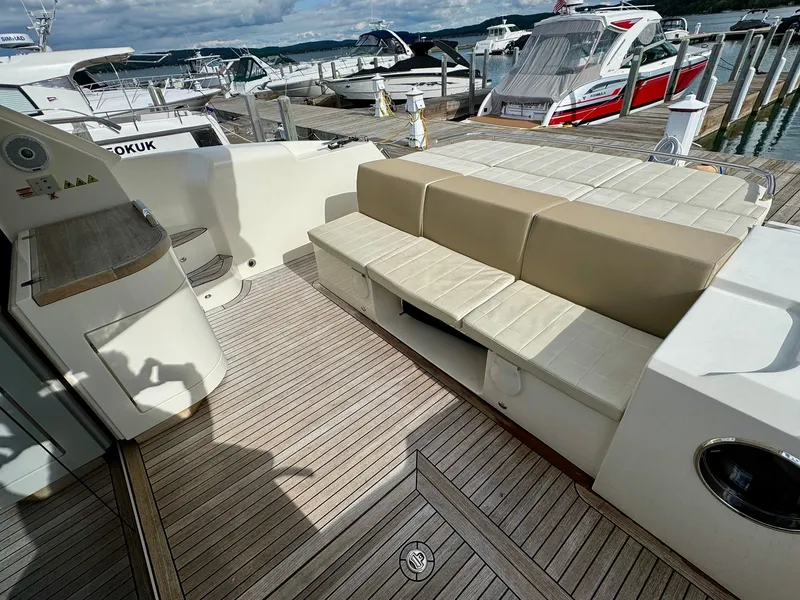 Slide: The Image of 2016 Absolute Sport Yacht deck with beige seating and wooden flooring at a marina. - 27