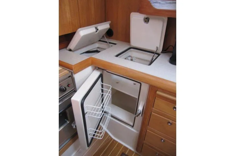 Slide: The Image of 2004 Catalina 350 MkII yacht kitchen with open fridge and storage compartments. - 26