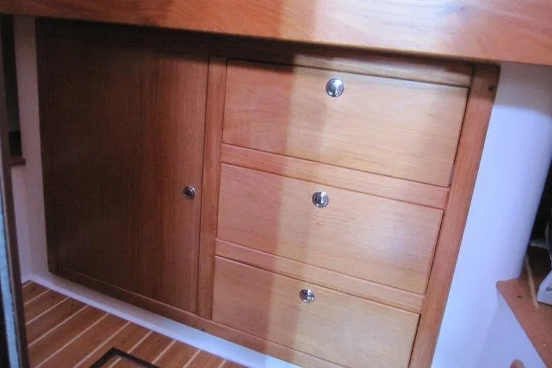Slide: The Image of Wooden cabinetry inside a 2004 Catalina 350 MkII sailboat, featuring drawers and a cabinet door. - 28