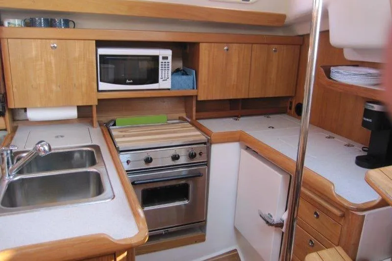 Slide: The Image of Compact kitchen in a 2004 Catalina 350 MkII sailboat with wooden cabinets and modern appliances. - 9