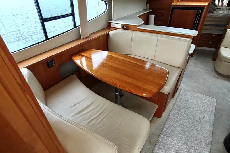 Slide: The Image of 2003 Silverton 330 Sport Bridge interior with wooden table and beige seating. - 10