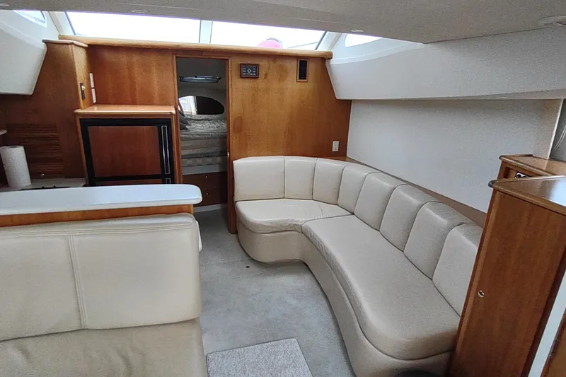 Slide: The Image of Interior of 2003 Silverton 330 Sport Bridge with beige seating and wood cabinetry. - 11