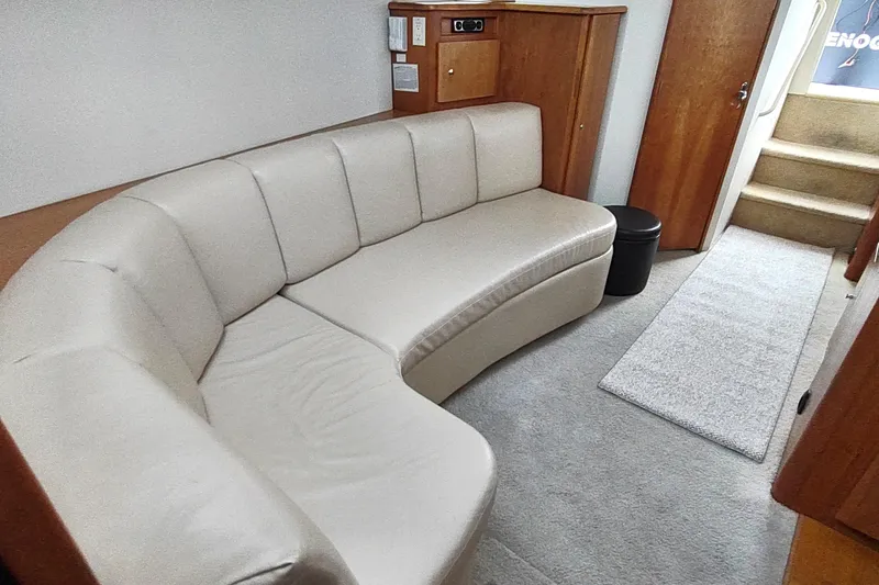 Slide: The Image of 2003 Silverton 330 Sport Bridge interior with cream leather sofa and wooden cabinetry. - 18