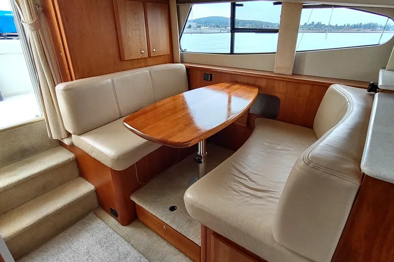 Slide: The Image of Interior of 2003 Silverton 330 Sport Bridge with cozy seating and wooden table. - 19