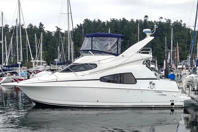 Slide: The Image of 2003 Silverton 330 Sport Bridge yacht docked in a marina, surrounded by sailboats. - 3