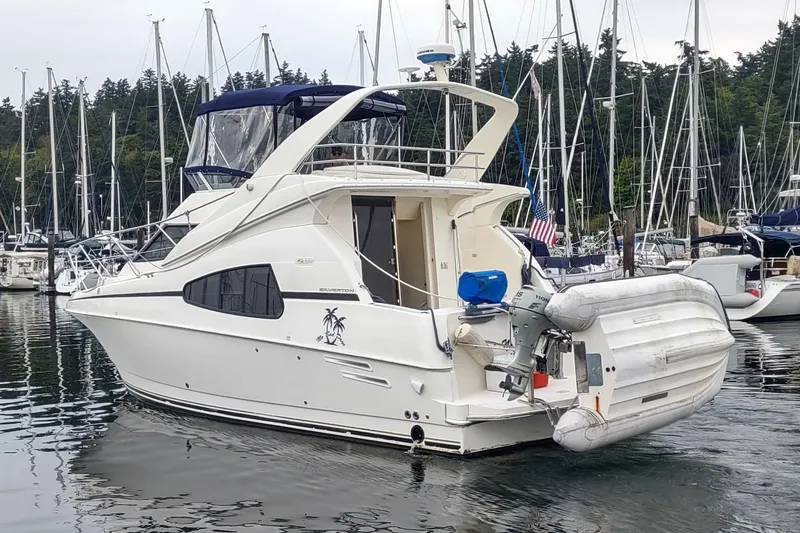 Slide: The Image of 2003 Silverton 330 Sport Bridge yacht docked in a marina with inflatable boat attached. - 4