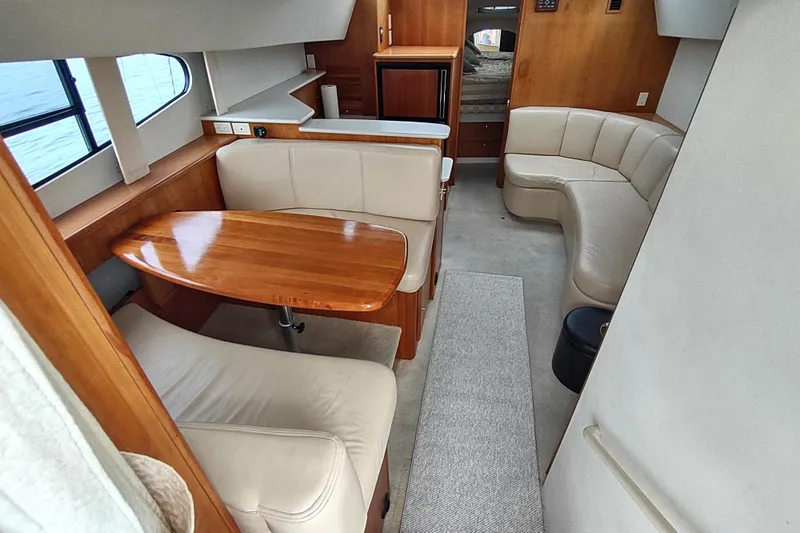 Slide: The Image of Interior of 2003 Silverton 330 Sport Bridge with cozy seating and wooden table. - 7