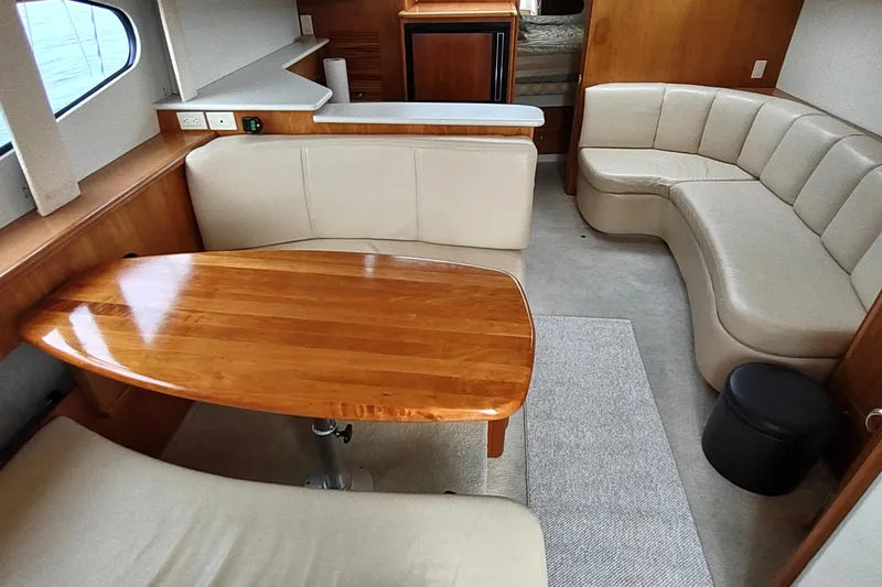 Slide: The Image of Interior of 2003 Silverton 330 Sport Bridge with wooden table and beige seating. - 8