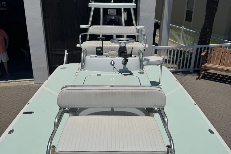 Slide: The Image of 2007 NewWater Ibis boat with white seating and steering console, docked near a building. - 12