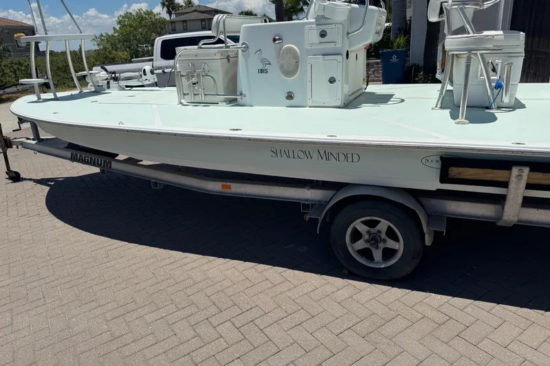 Slide: The Image of 2007 NewWater Ibis boat on trailer, labeled "Shallow Minded," parked on paved surface. - 2