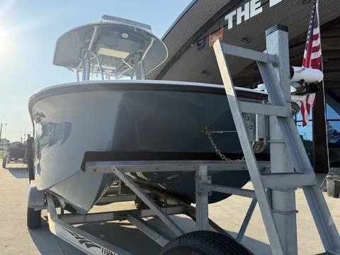 Slide: The Image of 2020 Tideline 235 Hybrid boat on trailer, parked outdoors near a building and American flag. - 2