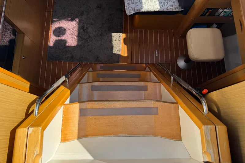 Slide: The Image of Interior view of 2009 Jeanneau Sun Odyssey 44i yacht, featuring wooden stairs and cozy cabin space. - 18