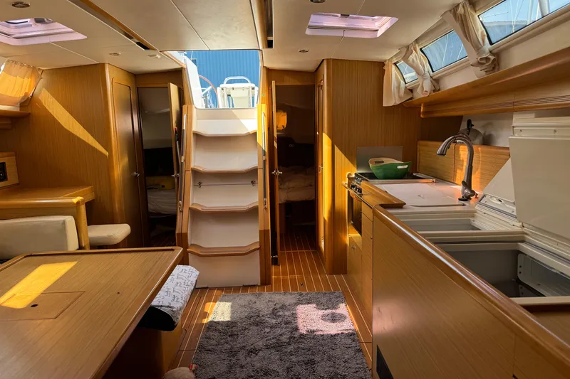 Slide: The Image of Interior of 2009 Jeanneau Sun Odyssey 44i sailboat, featuring a cozy kitchen and dining area. - 25