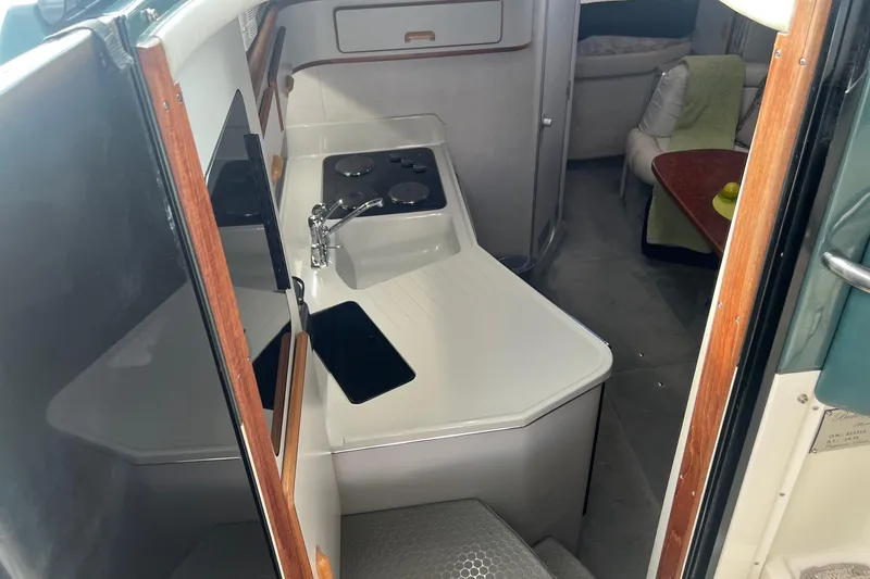 Slide: The Image of 1990 Sea Ray 350 Sundancer interior with compact kitchen and seating area. - 11