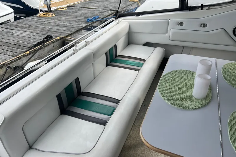 Slide: The Image of Interior of 1990 Sea Ray 350 Sundancer with cushioned seating and table, docked at marina. - 5
