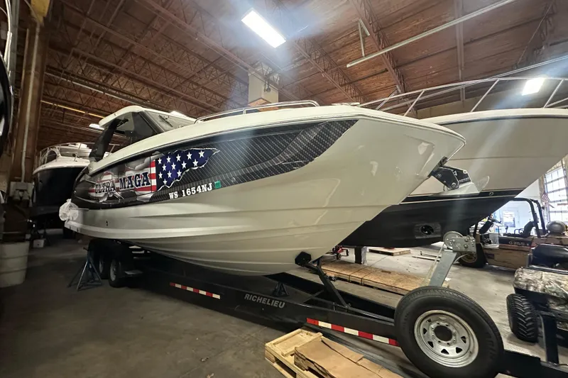 Slide: The Image of 2024 Galeon 325 GTO boat on trailer in warehouse, featuring American flag design. - 10