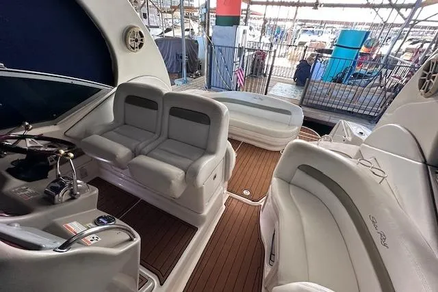 Slide: The Image of 2007 Sea Ray 320 Sundancer interior with plush seating and wood flooring at a marina. - 23