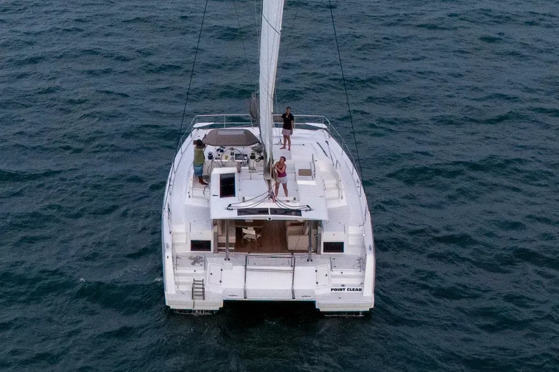 Slide: The Image of 2023 Bali 4.4 catamaran sailing on open sea with three people on deck. - 3