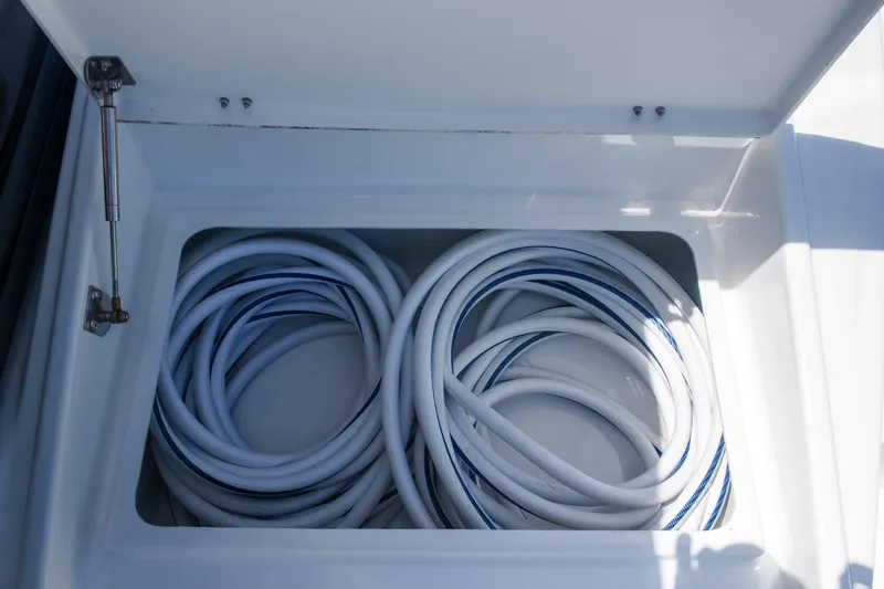 Slide: The Image of Storage compartment with coiled hoses on a 2023 Bali 4.4 model boat. - 44