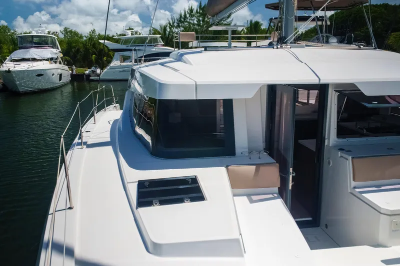 Slide: The Image of 2023 Bali 4.4 yacht docked in a marina, surrounded by lush greenery and other boats. - 58