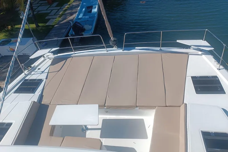 Slide: The Image of 2023 Bali 4.4 yacht deck with beige sun loungers and table, docked by the water. - 7