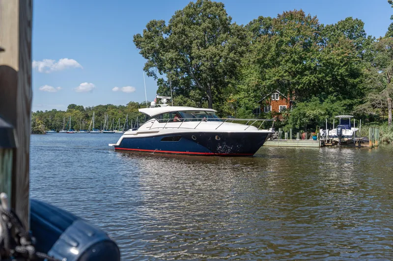 Slide: The Image of 2015 Tiara Yachts C44 Coupe cruising on a scenic river with lush greenery. - 2
